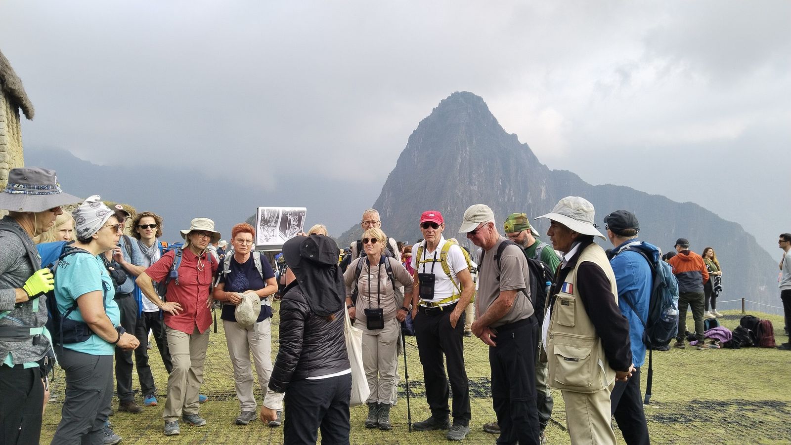 A guide explaining the site to the group above Machu Picchu